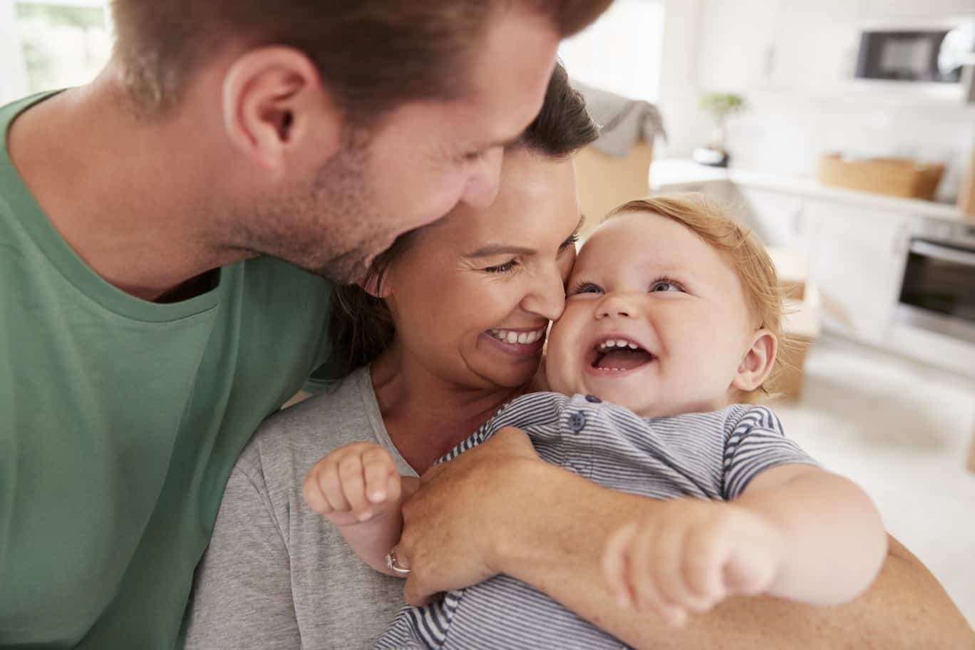 Parents Hugging Happy Baby Son At Home